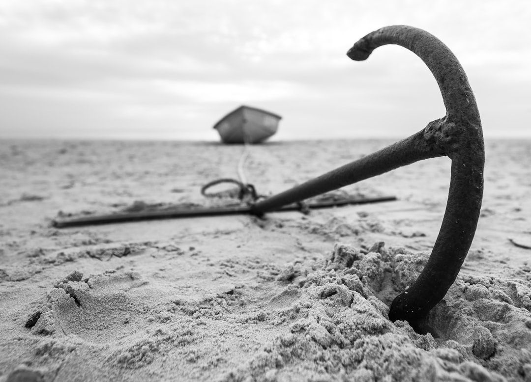 Närbild av ett akterankare nedgrävt i sand vid en strand