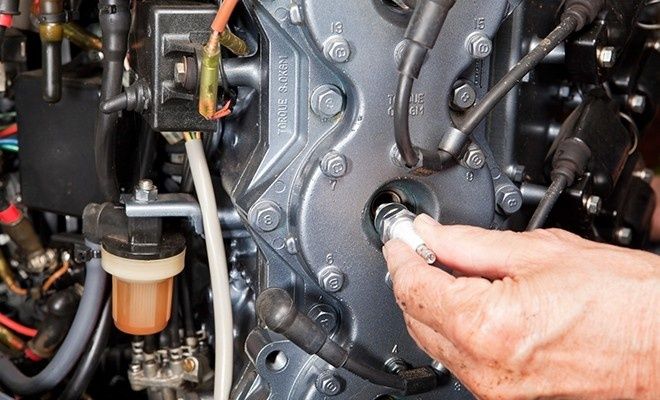 Hand som lossar ett tändstift på en utombordsmotor